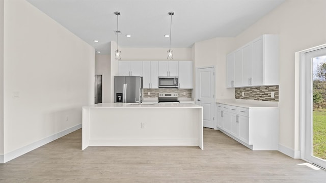 kitchen with stainless steel appliances, white cabinetry, and a center island with sink