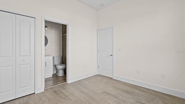 unfurnished bedroom featuring light hardwood / wood-style floors, a closet, and ensuite bathroom