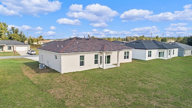 back of property with central AC and a lawn