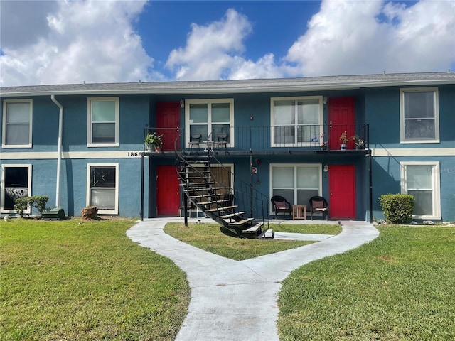 townhome / multi-family property featuring stucco siding, stairs, and a front yard