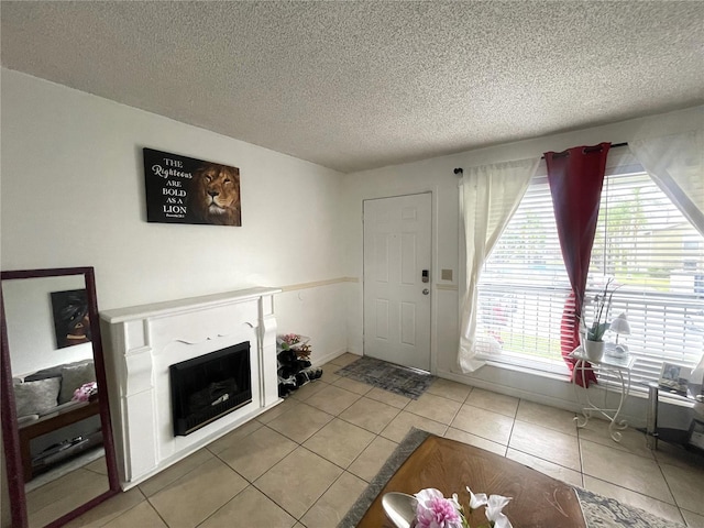 unfurnished living room with a textured ceiling, plenty of natural light, a fireplace, and tile patterned flooring