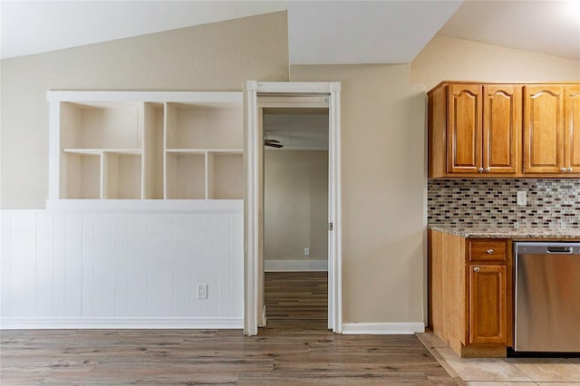 kitchen featuring light wood-style floors, vaulted ceiling, stainless steel dishwasher, backsplash, and brown cabinets