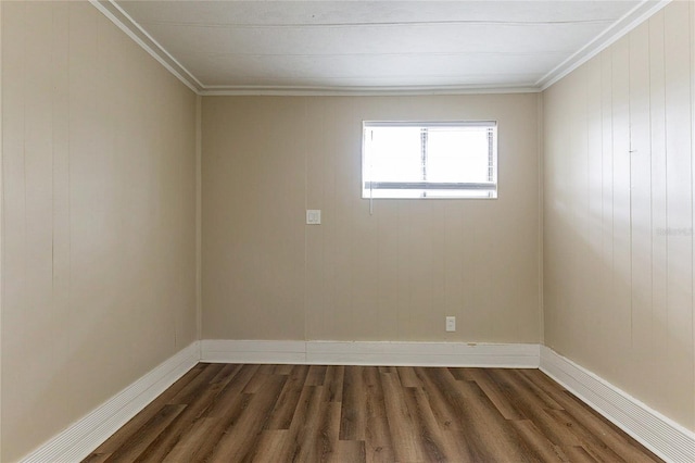 spare room featuring dark wood-style floors, crown molding, and baseboards