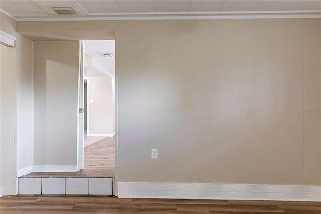 spare room featuring visible vents, wood finished floors, and ornamental molding