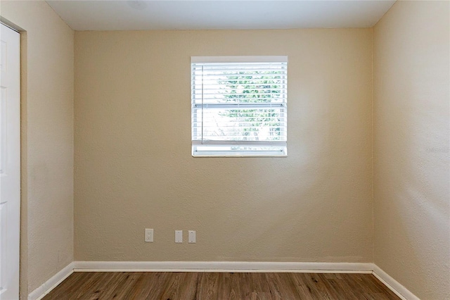 empty room featuring baseboards and dark wood-type flooring