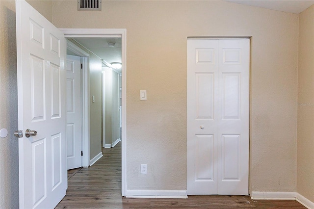 corridor featuring dark wood-style floors, lofted ceiling, visible vents, and baseboards