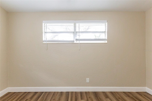 unfurnished room featuring a wealth of natural light, baseboards, and wood finished floors