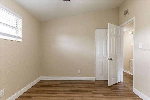 spare room with wood finished floors, visible vents, and baseboards