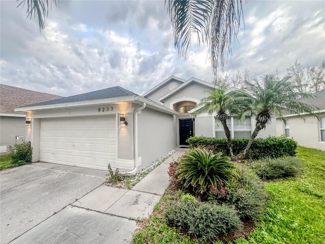 single story home with a garage, driveway, roof with shingles, and stucco siding