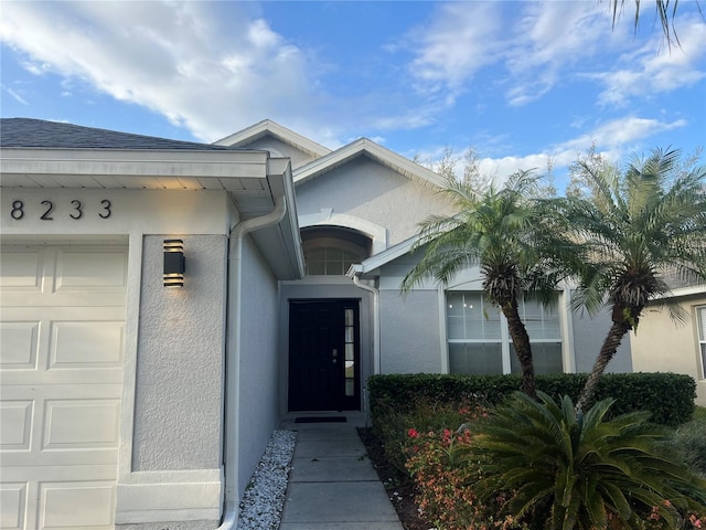 doorway to property with a garage and stucco siding