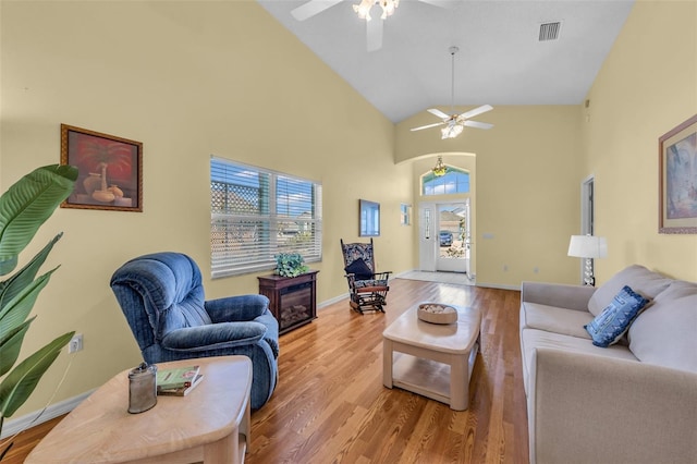 living area featuring baseboards, visible vents, a ceiling fan, wood finished floors, and high vaulted ceiling