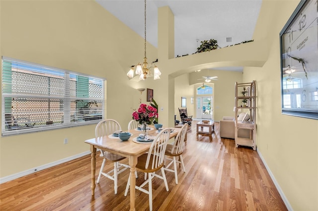 dining area with a ceiling fan, arched walkways, light wood-style flooring, and baseboards