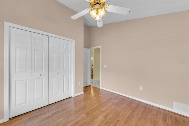 unfurnished bedroom featuring baseboards, a ceiling fan, lofted ceiling, light wood-style flooring, and a closet