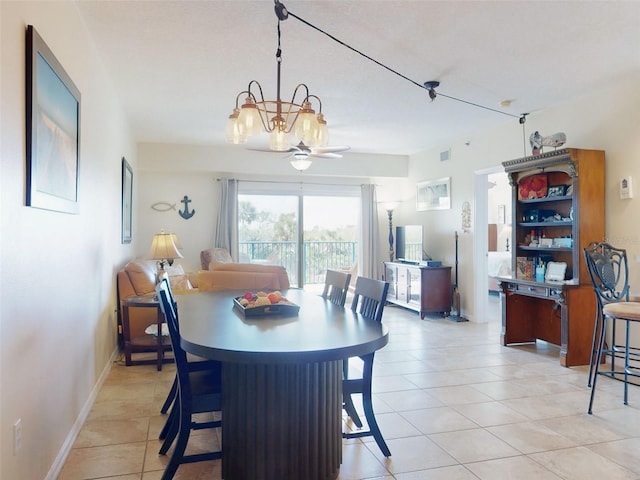 tiled dining room with ceiling fan with notable chandelier