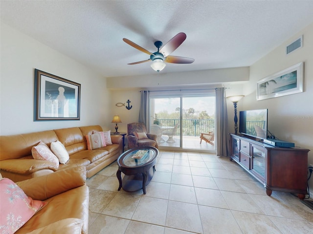 living room featuring ceiling fan, a textured ceiling, and light tile patterned floors