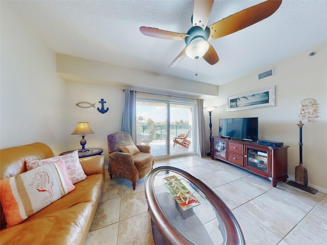 tiled living room featuring ceiling fan and a textured ceiling