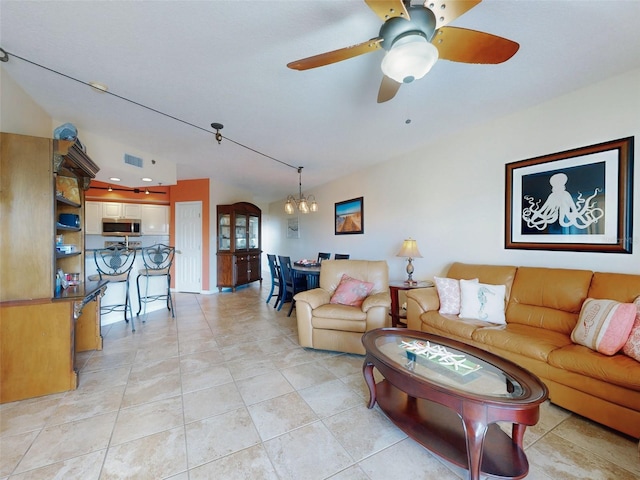 living room featuring light tile patterned flooring and ceiling fan with notable chandelier