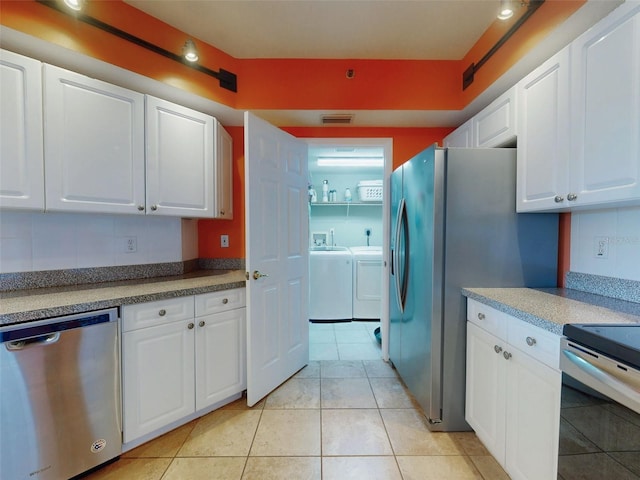 kitchen featuring appliances with stainless steel finishes, washer and clothes dryer, and white cabinets