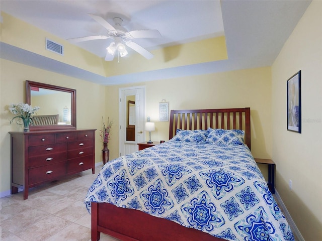 tiled bedroom with a raised ceiling and ceiling fan