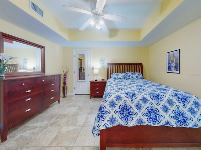 bedroom with light tile patterned flooring, ceiling fan, and a tray ceiling