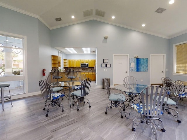 dining room with crown molding and high vaulted ceiling