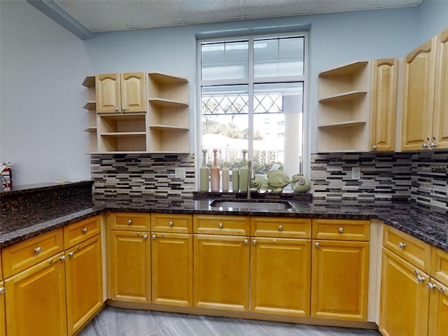 kitchen with sink, dark stone countertops, and backsplash