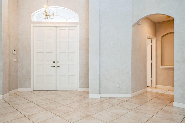 tiled entryway featuring a notable chandelier