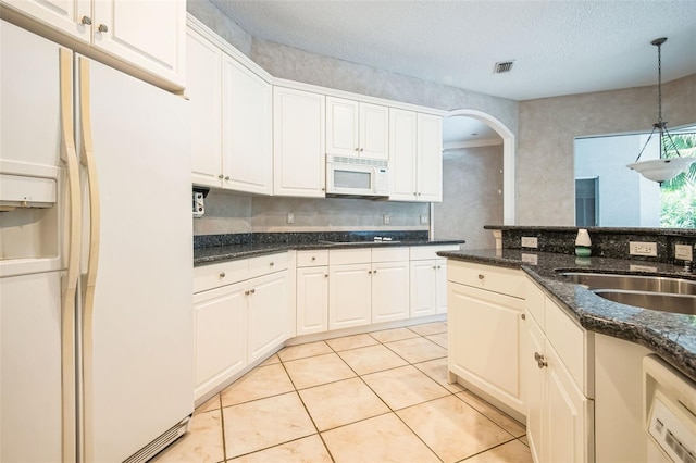 kitchen with white appliances, decorative light fixtures, and white cabinets