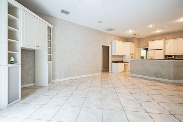 kitchen featuring white cabinetry and white fridge with ice dispenser