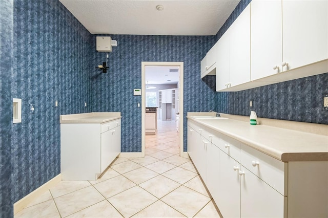 interior space featuring sink, a textured ceiling, and light tile patterned flooring