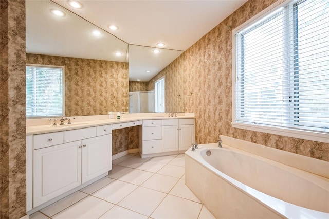 bathroom with a healthy amount of sunlight, independent shower and bath, tile patterned flooring, and vanity