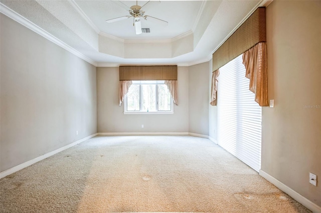 carpeted empty room featuring a raised ceiling, crown molding, and ceiling fan