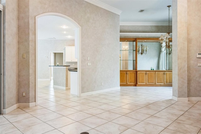 tiled spare room featuring crown molding and a chandelier