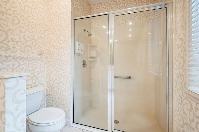 bathroom featuring a shower with door and toilet