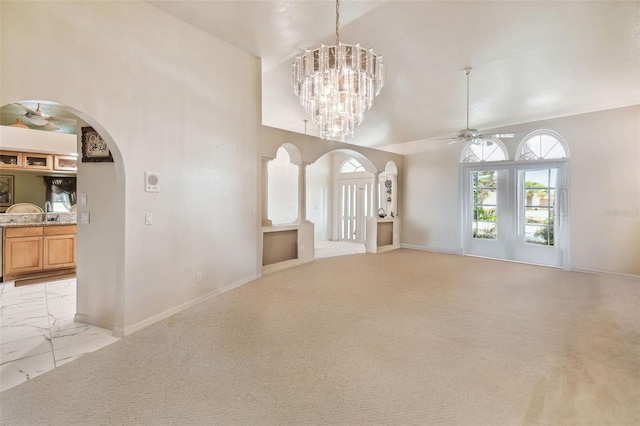 interior space with light carpet, ceiling fan with notable chandelier, and high vaulted ceiling