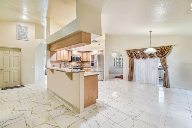 kitchen with appliances with stainless steel finishes, backsplash, a kitchen bar, light stone counters, and kitchen peninsula