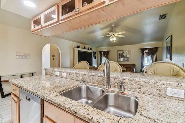 kitchen with light stone counters, sink, dishwasher, and ceiling fan