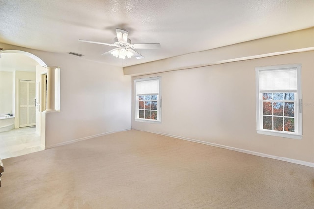 spare room featuring decorative columns, ceiling fan, light carpet, and a textured ceiling