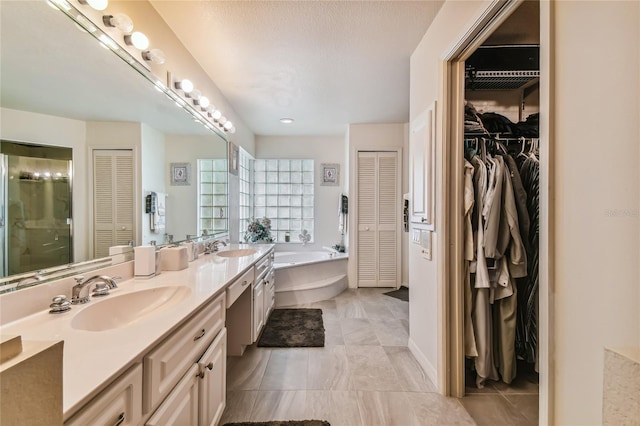 bathroom featuring vanity, a bath, and a textured ceiling