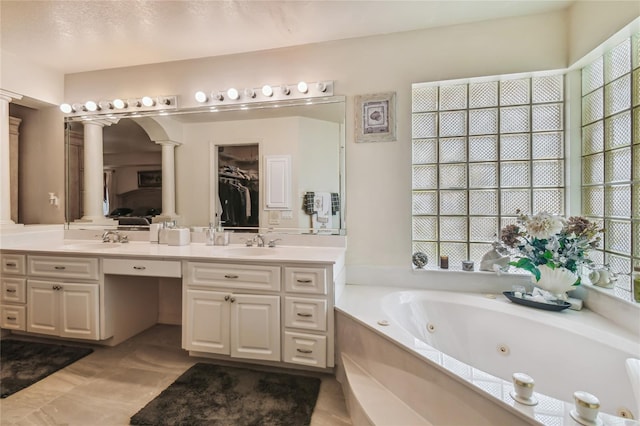 bathroom with vanity, tile patterned floors, decorative columns, and a tub