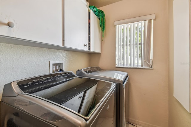 clothes washing area with cabinets and independent washer and dryer