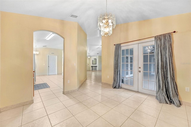 tiled empty room with vaulted ceiling, an inviting chandelier, and french doors