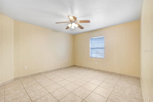 empty room with a textured ceiling, ceiling fan, and light tile patterned flooring