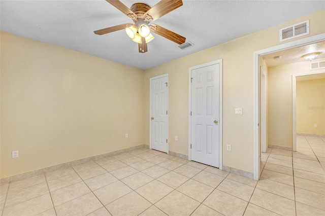 unfurnished bedroom with light tile patterned flooring, a textured ceiling, and ceiling fan