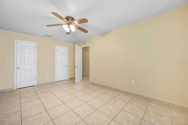 unfurnished bedroom featuring ceiling fan, a textured ceiling, and light tile patterned floors