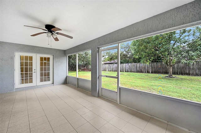 unfurnished sunroom featuring ceiling fan and french doors