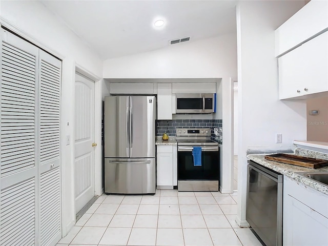 kitchen featuring lofted ceiling, light tile patterned floors, white cabinetry, stainless steel appliances, and decorative backsplash