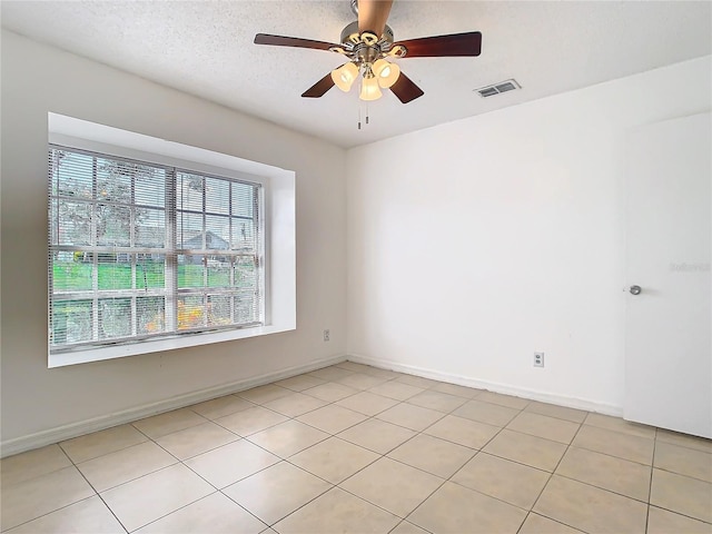 spare room with ceiling fan, light tile patterned floors, and a textured ceiling