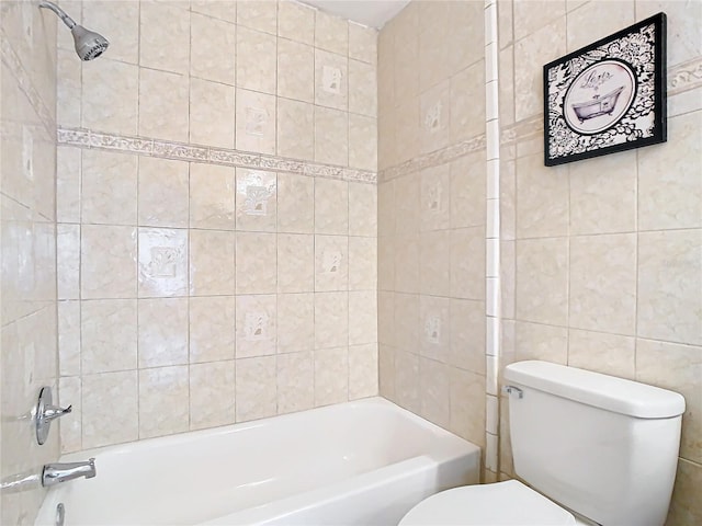 bathroom featuring tile walls, tiled shower / bath, and toilet