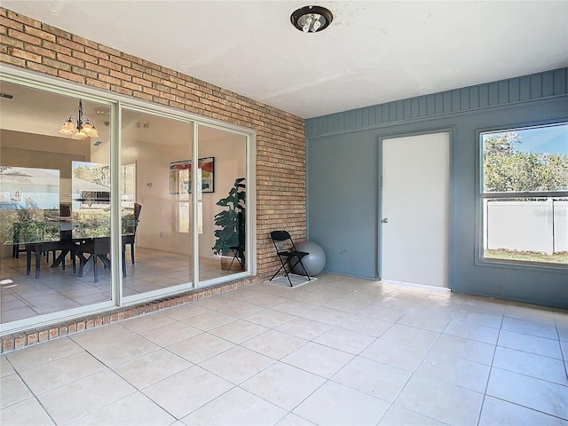 tiled spare room featuring brick wall